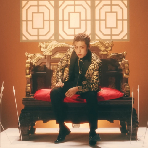 Image shows a Korean man sitting in a throne like love seat on a platform with arrows in the ground around him