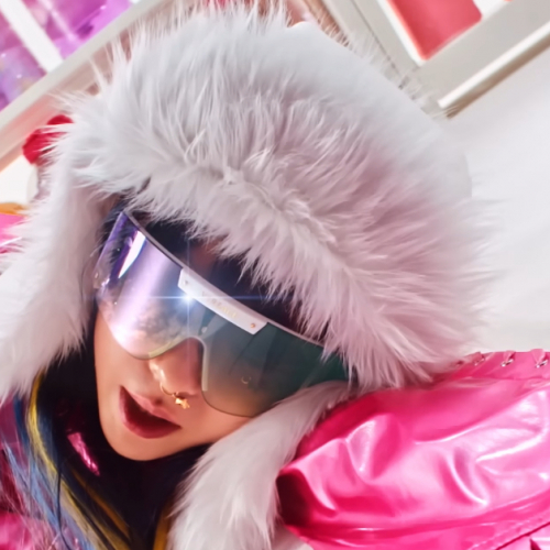 image shows a Korean women laying on a floor. She is wearing a fur hoodie, oversized sunglasses, and a pink vinyl coat