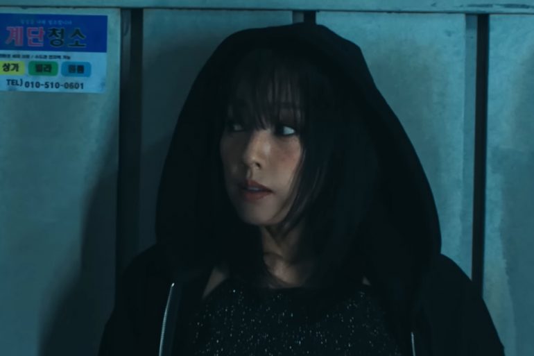Lee Hyori is wearing a hoodie with the hood over her head, and is leaning against a wall