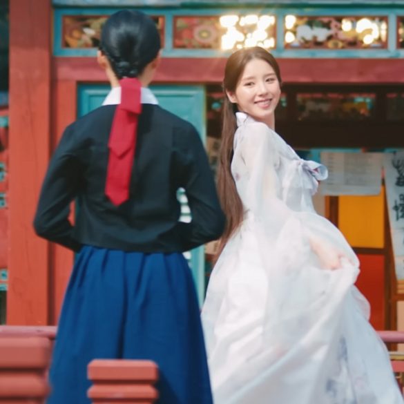 HeeJin is wearing a white hanbok in a Korean Temple. There are other women wearing hanbok around her