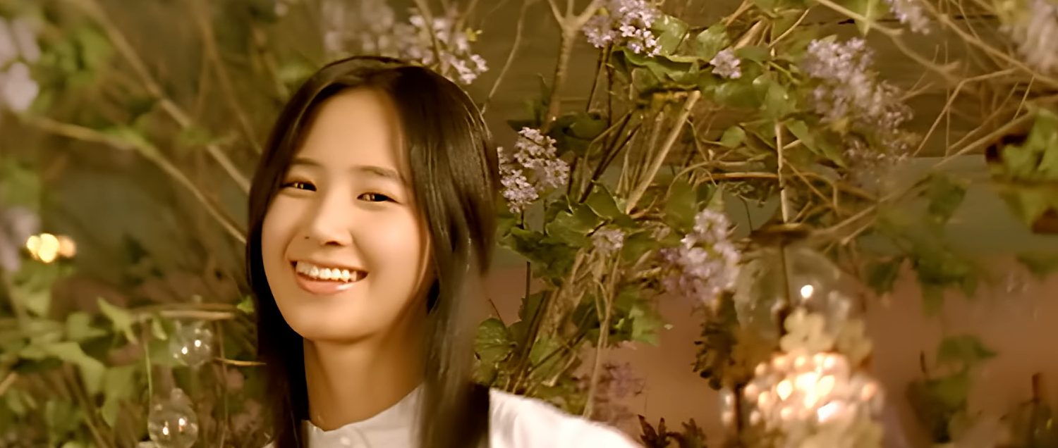 SNSD member Yuri stands in front of plants while smiling at the camera