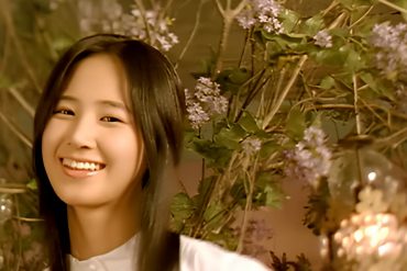 SNSD member Yuri stands in front of plants while smiling at the camera