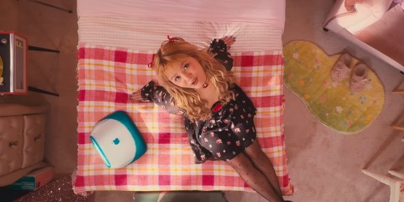 SORN sits on a bed in a very pink room. There's aa variety of items around the room like an iMAC, turntable, slippers, a Tube TV, and more.