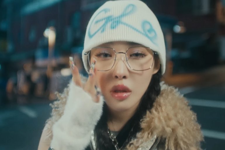 Chung Ha is looking at the camera while adjusting her glasses.