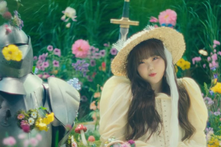 Su-hyun of AKMU sits in a field of flowers next to a knight.